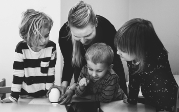 Grayscale Photo of Mother and Three Children Playing