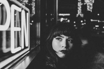 grayscale photo of woman beside open signage