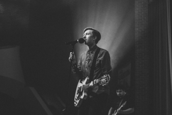Grayscale Photography of Person Near on Pedestal Microphone