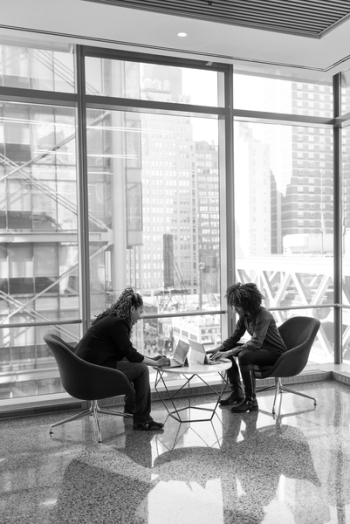 Grayscale Portrait of Two People Sitting on Chairs