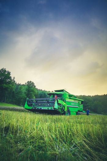 Green Harvester on Green Rice Field Under Blue and White Sky during Daytime