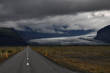 grey asphalt road under dark cloudy sky grey asphalt road under dark cloudy sky