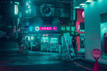 group of people walking on the street near buildings at night time