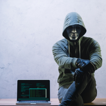 Hacker sitting next to laptop Hacker sitting next to laptop
