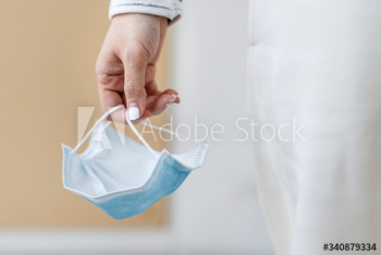Hand holding a used face mask during coronavirus pandemic Hand holding a used face mask during coronavirus pandemic
