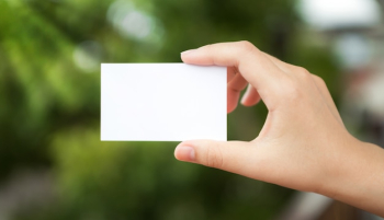 Hand holding a white paper with the background defocused