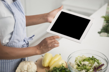 Hands holding a photo mock up next to vegetables Free Photo