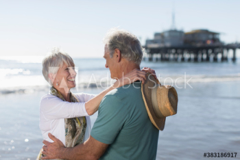 Happy active senior couple hugging on sunny ocean beach Happy active senior couple hugging on sunny ocean beach