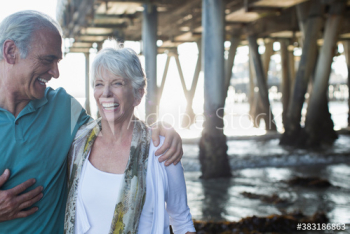 Happy active senior couple on ocean beach below pier Happy active senior couple on ocean beach below pier