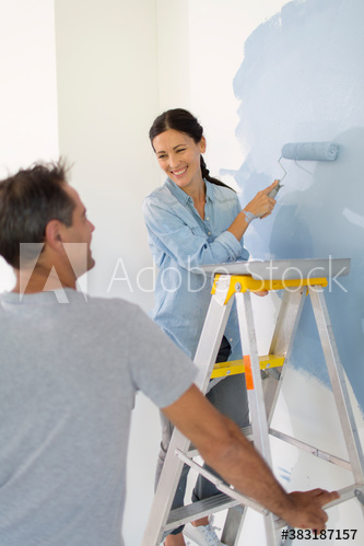 Happy couple painting wall with blue paint Happy couple painting wall with blue paint