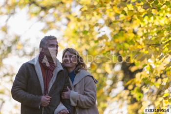 Happy couple walking arm in arm in autumn park Happy couple walking arm in arm in autumn park