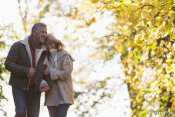 Happy couple walking arm in arm in autumn park Happy couple walking arm in arm in autumn park