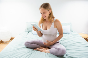 Happy expectant mom reading on tablet screen Free Photo