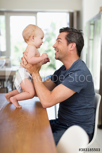 Happy father holding baby son at dining table Happy father holding baby son at dining table