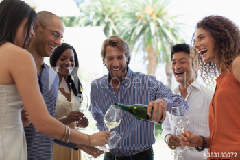 Happy friends drinking white wine at social gathering