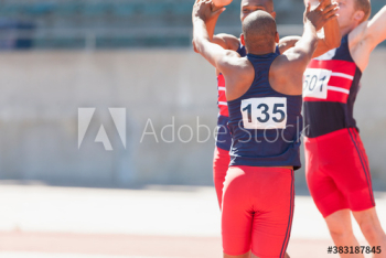 Happy male track and field team celebrating on sunny running track Happy male track and field team celebrating on sunny running track