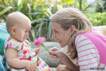 Happy mother showing pink rose to baby daughter Happy mother showing pink rose to baby daughter