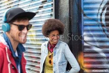 Happy young man and woman laughing against graffiti wall Happy young man and woman laughing against graffiti wall
