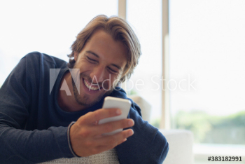 Happy young man laughing and using smart phone Happy young man laughing and using smart phone
