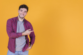 Happy young man pointing his finger against yellow backdrop Free Photo