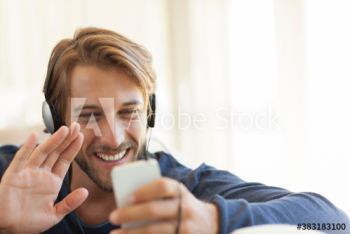Happy young man video chatting with smart phone and headphones Happy young man video chatting with smart phone and headphones