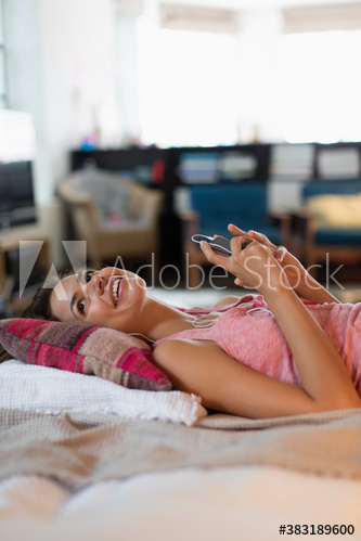 Happy young woman listening to music on bed Happy young woman listening to music on bed