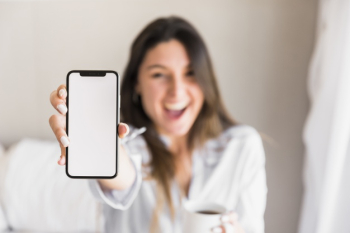 Happy young woman showing white screen mobile phone Free Photo