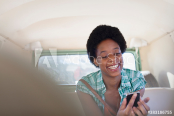 Happy young woman using smart phone inside van Happy young woman using smart phone inside van