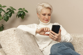 High angle senior female on couch using phone Free Photo