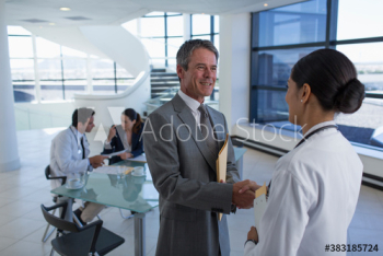 Hospital administrator shaking hands with doctor in meeting Hospital administrator shaking hands with doctor in meeting