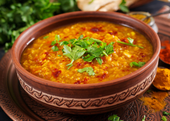 Indian dhal spicy curry in bowl, spices, herbs, rustic black wooden table Free Photo