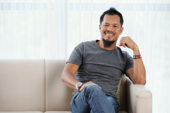 Joyful filipino man seated on couch smiling contentedly at camera Free Photo Joyful filipino man seated on couch smiling contentedly at camera Free Photo