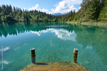 Landscape panorama of Crestasee - Lake Cresta in June, municipalities of Flims and Trin in the Grisons, Switzerland. Wooden dock on the lake.      