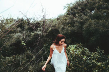 landscape photography of woman behind green leafed trees during daytime