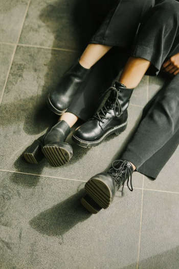 Legs in Black Shoes and Pants of Two Unrecognizable Persons Sitting on Floor · Free Stock Photo