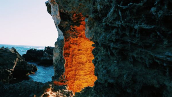 lighted cave entrance near body of water lighted cave entrance near body of water