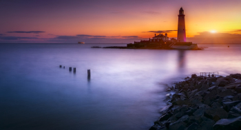 Lighthouse On Island Under Orange Sunset Lighthouse On Island Under Orange Sunset