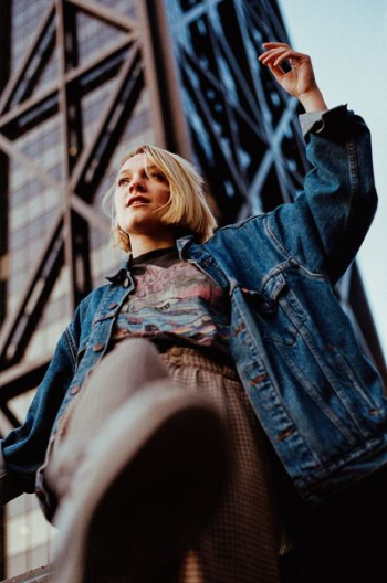 low-angle photography of woman standing near building outdoor during daytime