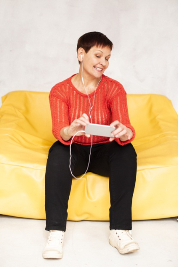 Low angle senior female on couch listening music Free Photo