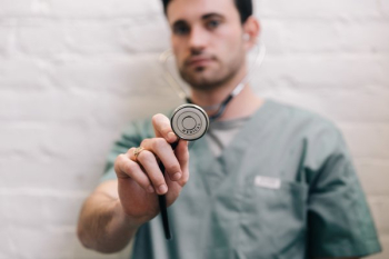Male Doctor Holding Out Stethoscope