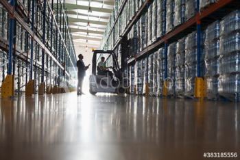 Male supervisor and worker operating forklift in distribution warehouse Male supervisor and worker operating forklift in distribution warehouse
