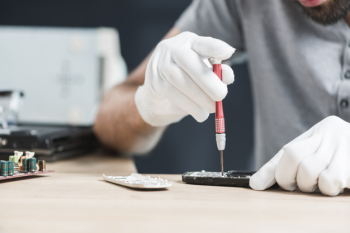 Male technician repairing cellphone over wooden desk Male technician repairing cellphone over wooden desk