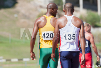Male track and field athletes on sunny running track Male track and field athletes on sunny running track