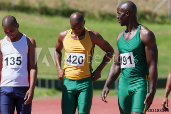 Male track and field athletes on sunny running track Male track and field athletes on sunny running track