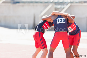 Male track and field team in huddle on sunny running track Male track and field team in huddle on sunny running track