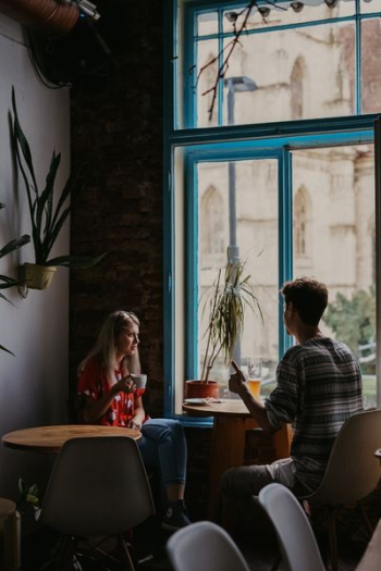 man and woman in front of round brown wooden pedestal table man and woman in front of round brown wooden pedestal table