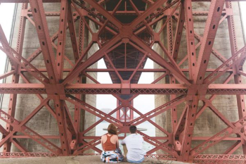 man and woman sitting near red metal scaffolding during daytime man and woman sitting near red metal scaffolding during daytime