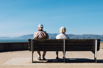 man and woman sitting on bench facing sea man and woman sitting on bench facing sea