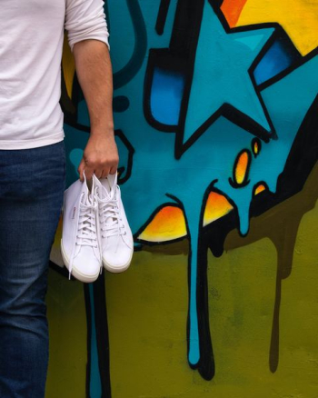 man carrying pair of white high-top sneakers man carrying pair of white high-top sneakers