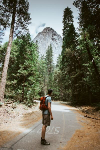 man carrying red camping backpack near mountain man carrying red camping backpack near mountain